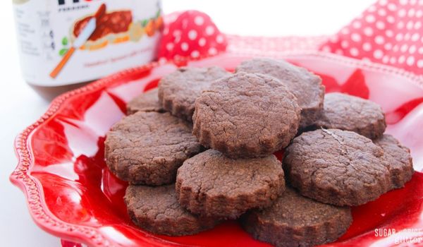 nutella cookies on a red plate with a jar of nutella in the background