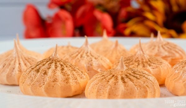 pumpkin meringues dusted with pumpkin pie spice on a white plate