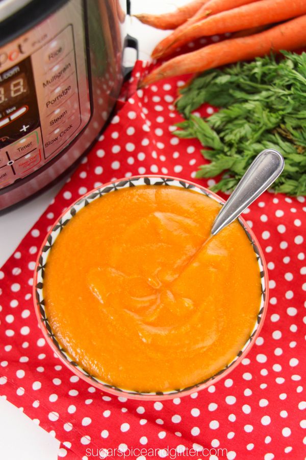 overhead image of a black and white bowl filled with carrot ginger soup with carrots and an Instant Pot in the background