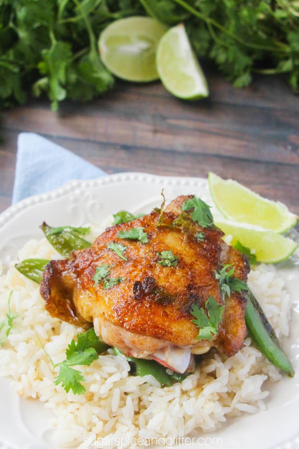 a golden lime cilantro chicken thigh on a bed of rice on a whilte plate