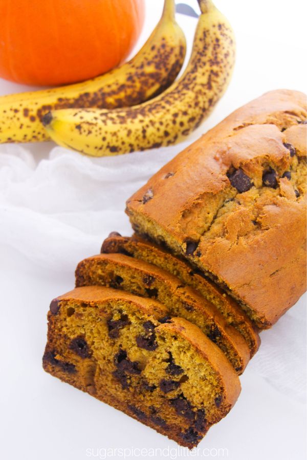 overhead image of pumpkin banana bread with chocolate chips with a pumpkin and bananas in the background