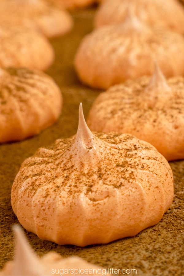 close-up image of pumpkin meringues dusted with pumpkin pie spice on parchment paper