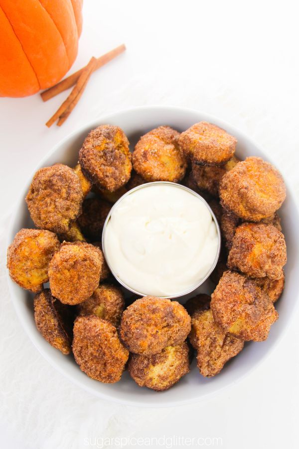 overhead image of a white bowl full of pumpkin spice pretzel bites with a small bowl of cream cheese dip in the centre