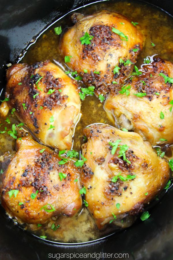 cooked brown sugar garlic chicken thighs in a black crockpot, sprinkled with parsley