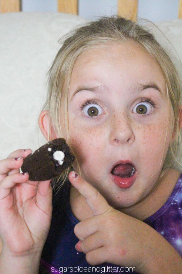 little girl holding a chocolate Twinkie with a bite taken out of it