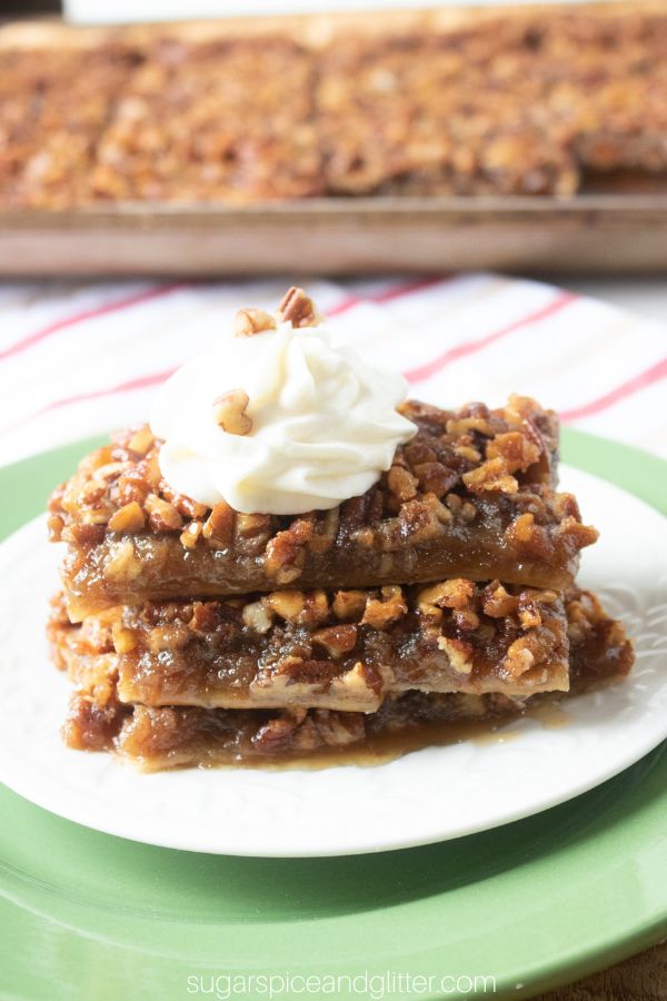 a stack of pecan pie square slices on a white plate, topped with a dollop of whipped cream