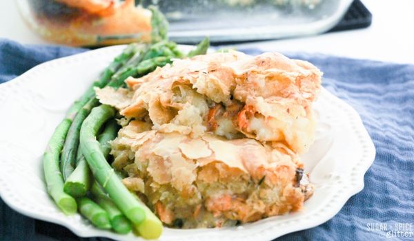 white plate on blue napkin with a serving of salmon pie alongside a serving of asparagus
