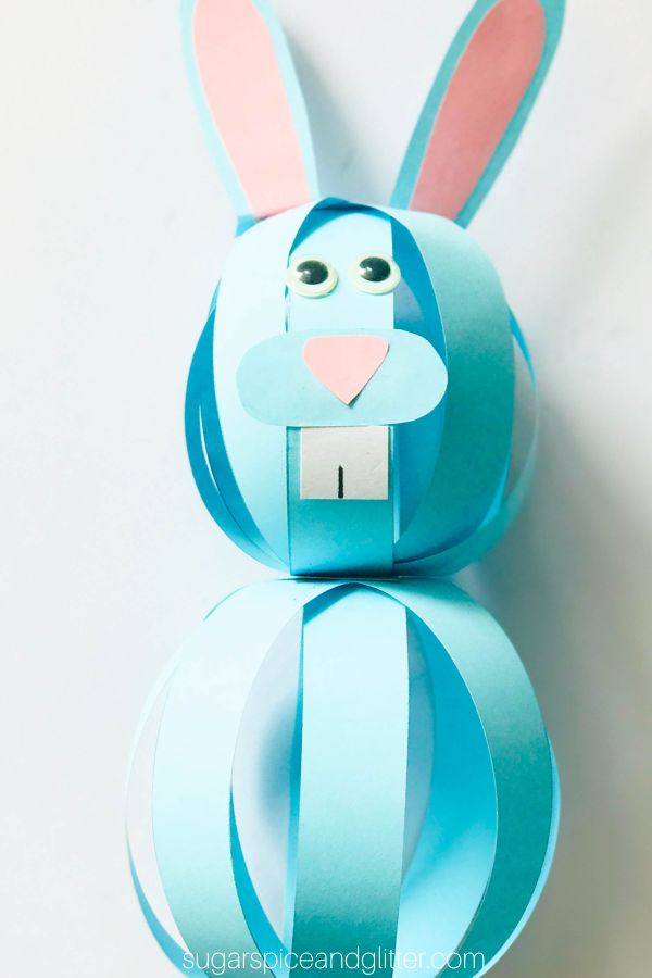 a blue paper bally bunny craft with googly eyes and a pink nose