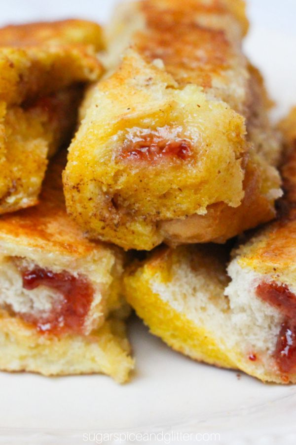 close-up of a stack of pb&j french toast roll ups on a white plate